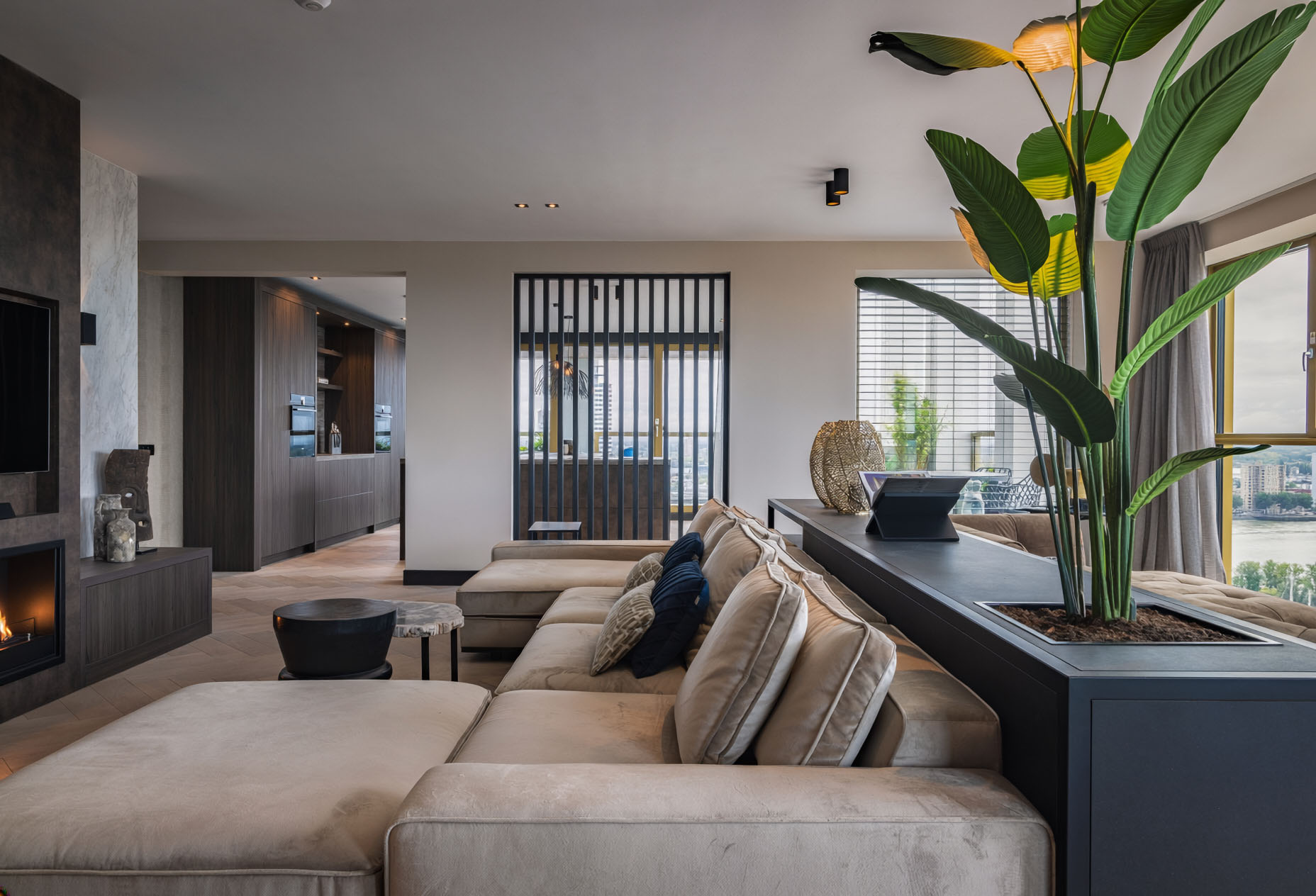 Luxurious modern penthouse living room with beige sectional sofa, tropical plants, and contemporary design