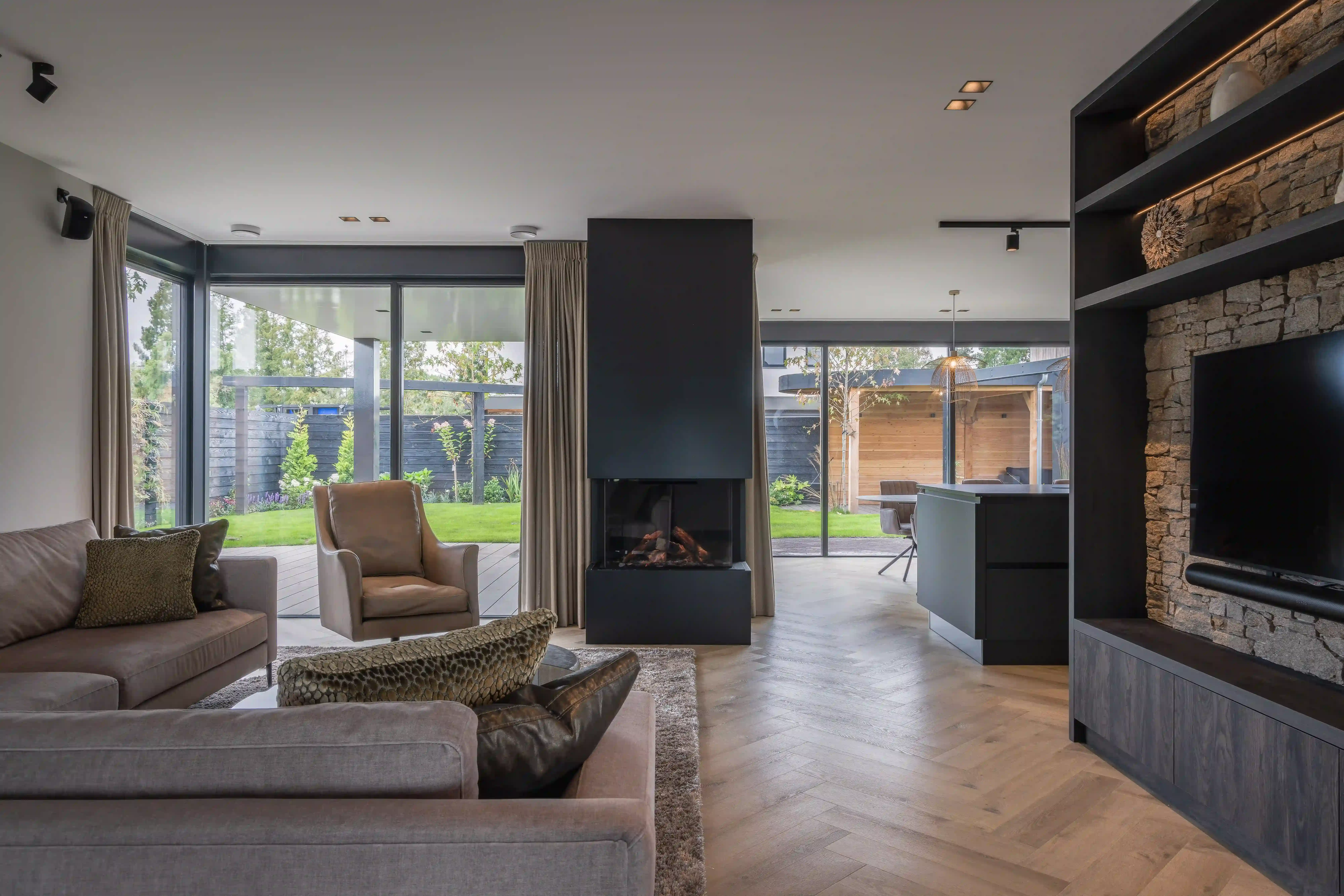 Villa Rotterdam - Woonkamer met tuinzicht, centrale haard en neutrale zithoek