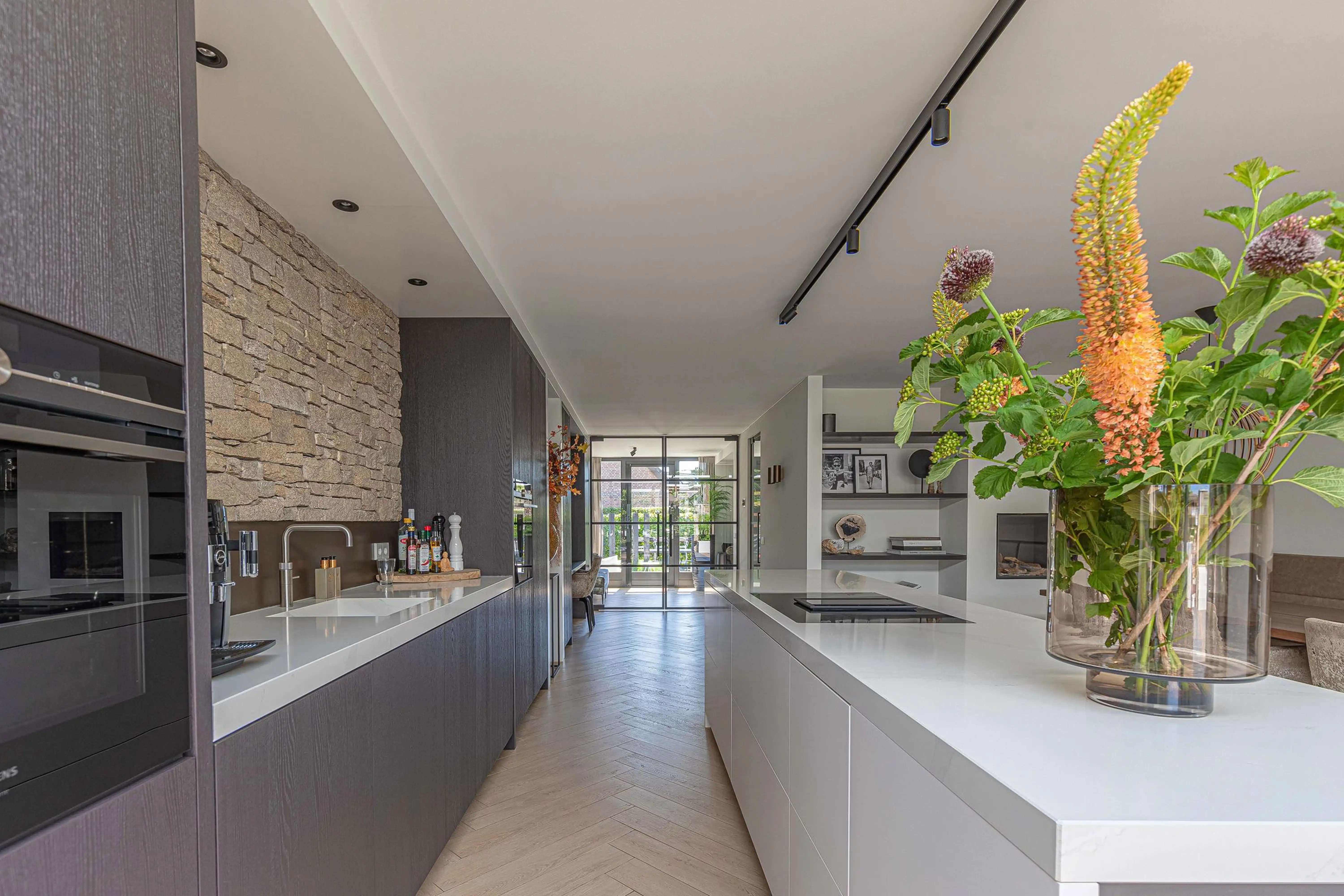 Wonen aan het water Reeuwijk 2 - Long kitchen view with flowers and double islands